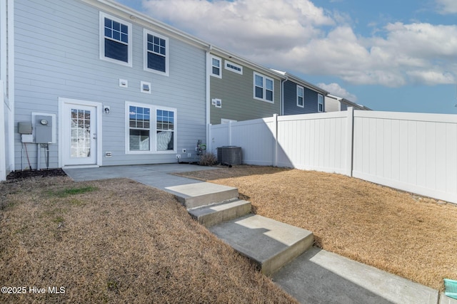 rear view of house with central AC unit and a patio