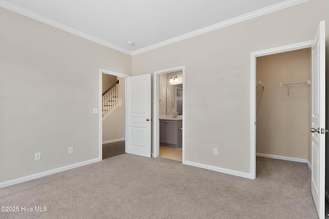 unfurnished bedroom featuring crown molding, connected bathroom, a walk in closet, light colored carpet, and a closet