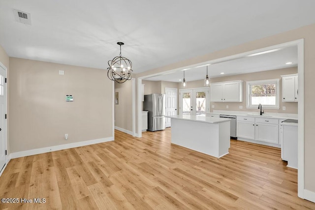 kitchen featuring pendant lighting, sink, appliances with stainless steel finishes, white cabinets, and a kitchen island