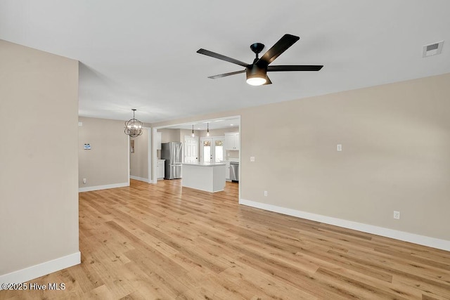 unfurnished living room with ceiling fan with notable chandelier and light wood-type flooring