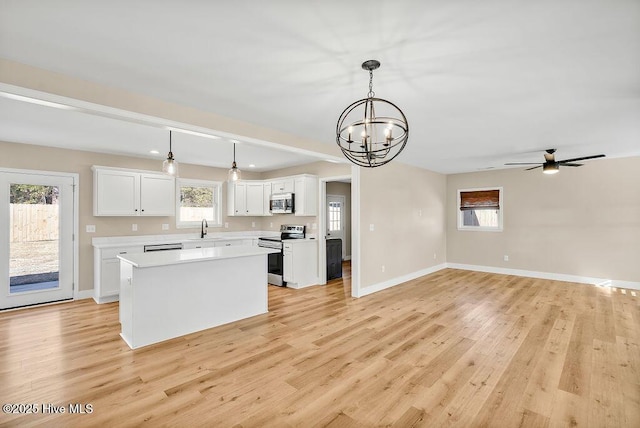 kitchen featuring decorative light fixtures, a center island, white cabinets, and appliances with stainless steel finishes