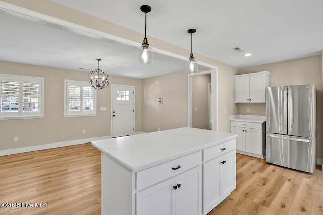 kitchen featuring white cabinetry, a center island, stainless steel refrigerator, and light wood-type flooring