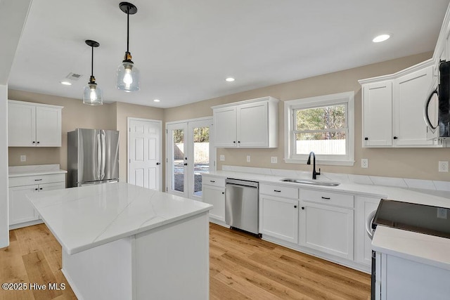 kitchen featuring sink, stainless steel appliances, a center island, and white cabinets