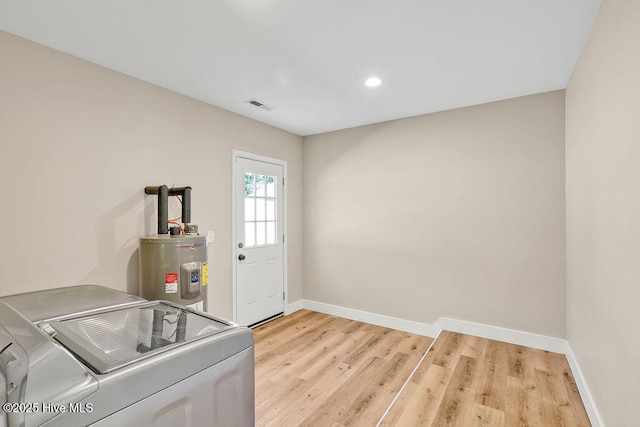 laundry area featuring separate washer and dryer, electric water heater, and light wood-type flooring