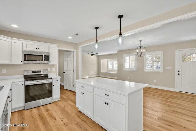 kitchen featuring hanging light fixtures, white cabinetry, appliances with stainless steel finishes, and light hardwood / wood-style flooring