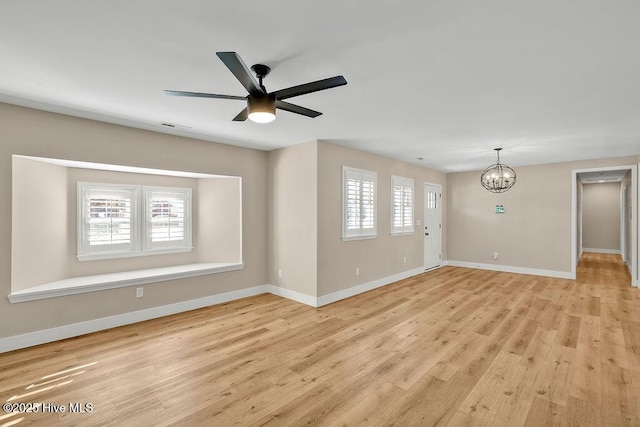 unfurnished living room with ceiling fan with notable chandelier and light wood-type flooring