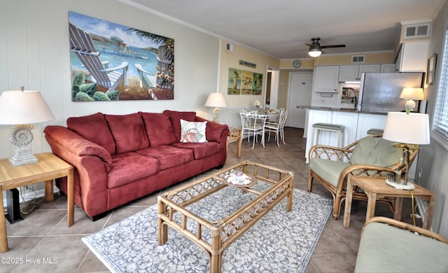 tiled living room featuring ceiling fan and ornamental molding