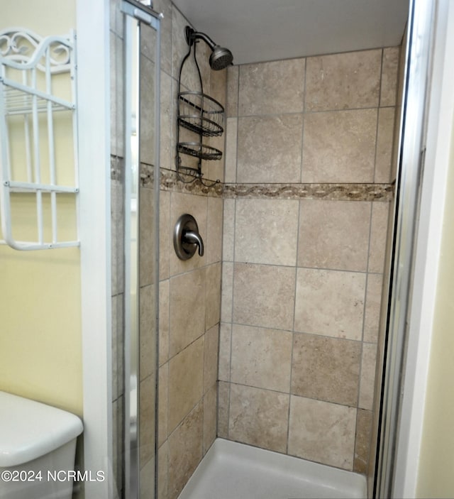 bathroom featuring tiled shower and toilet