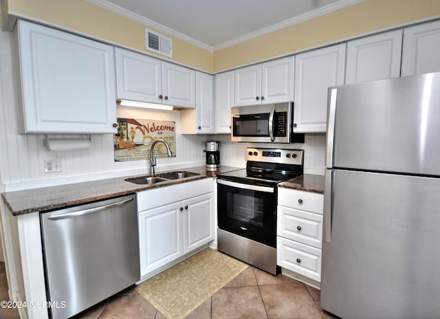 kitchen featuring white cabinetry, sink, dark stone counters, ornamental molding, and stainless steel appliances