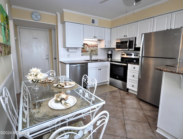 kitchen with tile patterned floors, sink, crown molding, stainless steel appliances, and white cabinets