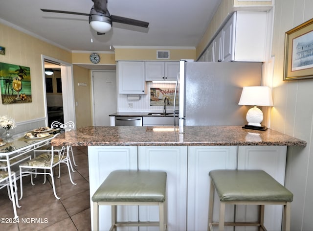 kitchen featuring sink, stainless steel appliances, kitchen peninsula, and a kitchen bar