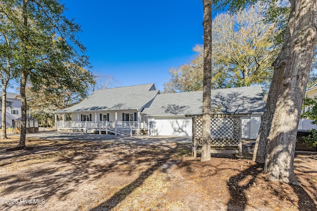 rear view of house featuring driveway, roof with shingles, and an attached garage