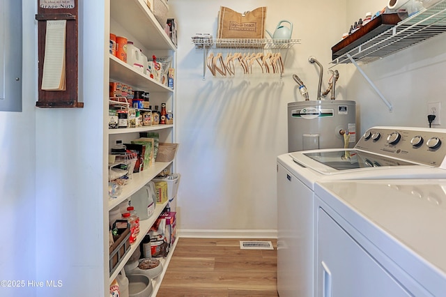 laundry area with visible vents, independent washer and dryer, water heater, light wood finished floors, and laundry area