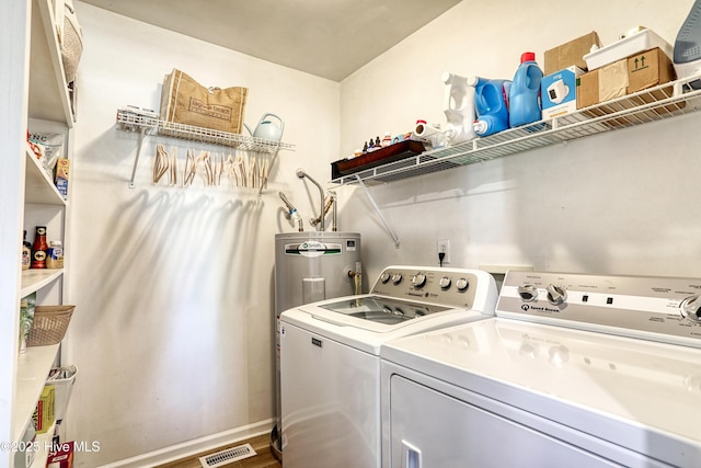 washroom with baseboards, visible vents, washing machine and clothes dryer, laundry area, and water heater