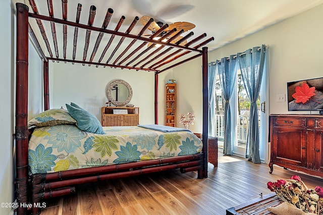 bedroom with wood finished floors, vaulted ceiling, and access to exterior