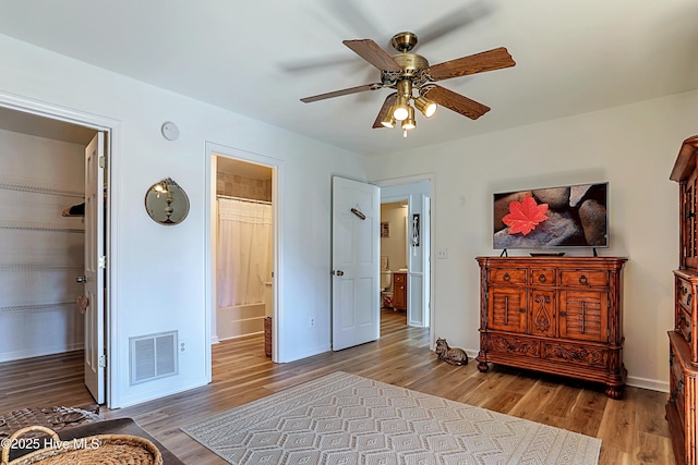 bedroom featuring visible vents, a ceiling fan, wood finished floors, connected bathroom, and baseboards