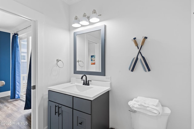 bathroom with vanity, wood-type flooring, ornamental molding, and toilet