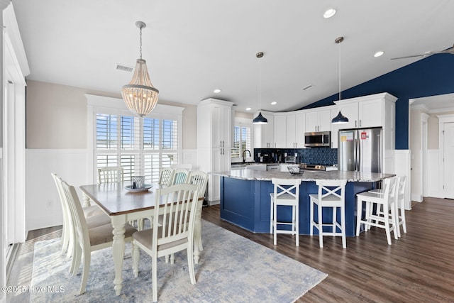 dining area featuring vaulted ceiling, an inviting chandelier, dark hardwood / wood-style floors, and sink