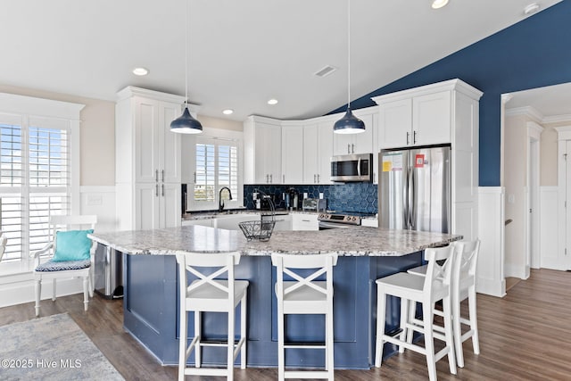 kitchen with white cabinetry, pendant lighting, a kitchen island, and appliances with stainless steel finishes