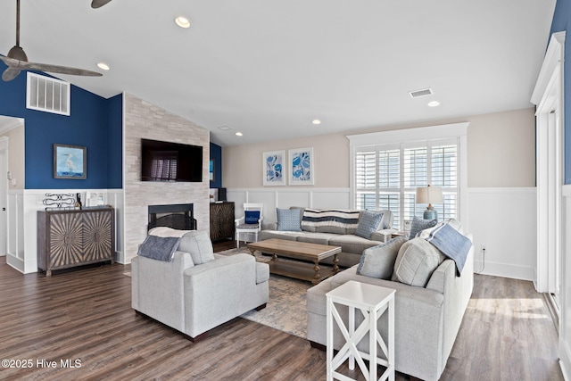 living room with ceiling fan, a large fireplace, lofted ceiling, and dark hardwood / wood-style flooring