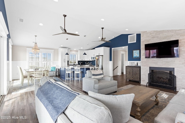 living room featuring a tile fireplace, vaulted ceiling, wood-type flooring, sink, and ceiling fan