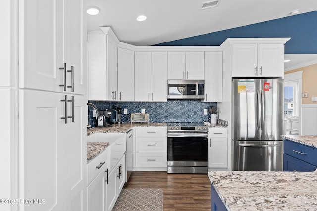 kitchen with light stone countertops, appliances with stainless steel finishes, white cabinets, and lofted ceiling