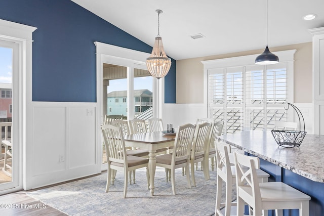 dining space featuring lofted ceiling, an inviting chandelier, and light hardwood / wood-style flooring