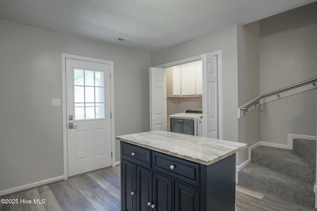 kitchen with light hardwood / wood-style flooring, a center island, and a textured ceiling