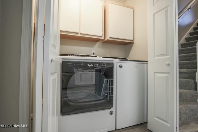 clothes washing area featuring washing machine and dryer and cabinets