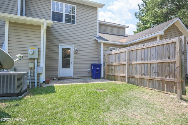 back of property with central AC unit and a lawn