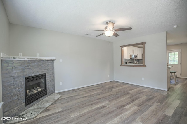 unfurnished living room featuring hardwood / wood-style flooring, ceiling fan, and a textured ceiling