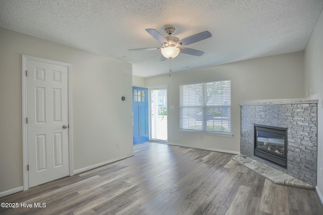 unfurnished living room featuring a fireplace, a textured ceiling, and light wood-type flooring