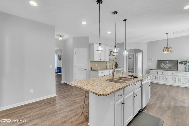 kitchen featuring white cabinetry, decorative light fixtures, an island with sink, and tasteful backsplash