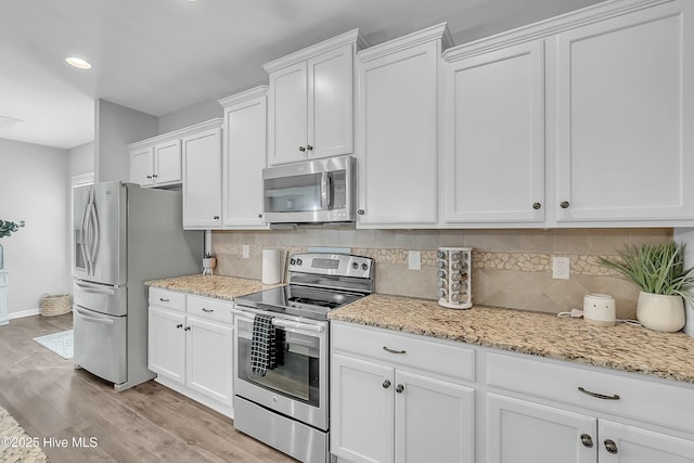 kitchen featuring light hardwood / wood-style flooring, appliances with stainless steel finishes, light stone countertops, decorative backsplash, and white cabinets