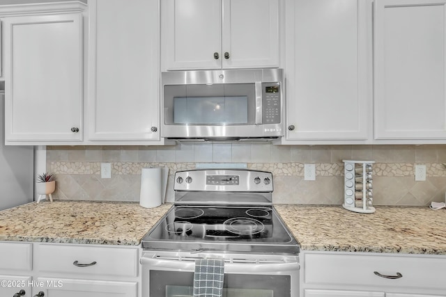 kitchen with backsplash, stainless steel appliances, white cabinets, and light stone countertops