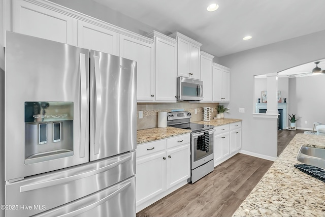 kitchen featuring appliances with stainless steel finishes, tasteful backsplash, white cabinets, ceiling fan, and light stone countertops