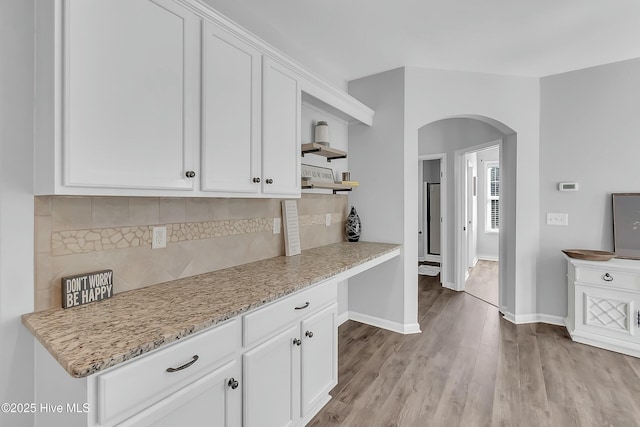 kitchen with white cabinetry, backsplash, and light stone counters