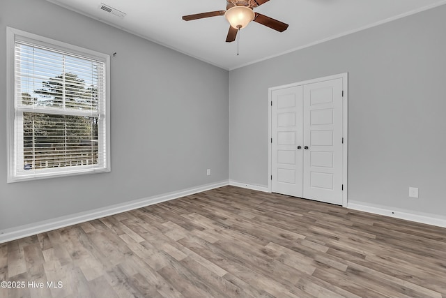 unfurnished bedroom with crown molding, light hardwood / wood-style floors, a closet, and ceiling fan