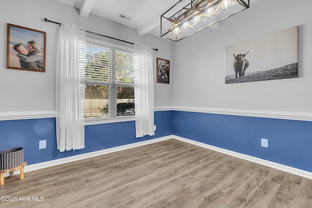 empty room with hardwood / wood-style flooring and beamed ceiling