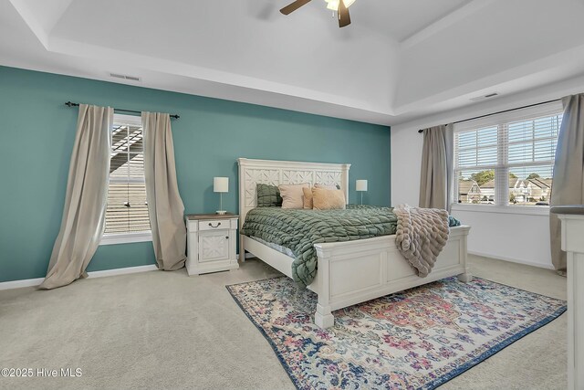 carpeted bedroom featuring a tray ceiling, vaulted ceiling, and ceiling fan