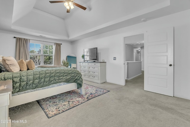 carpeted bedroom featuring a tray ceiling and ceiling fan