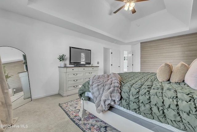 carpeted bedroom with a raised ceiling and ceiling fan