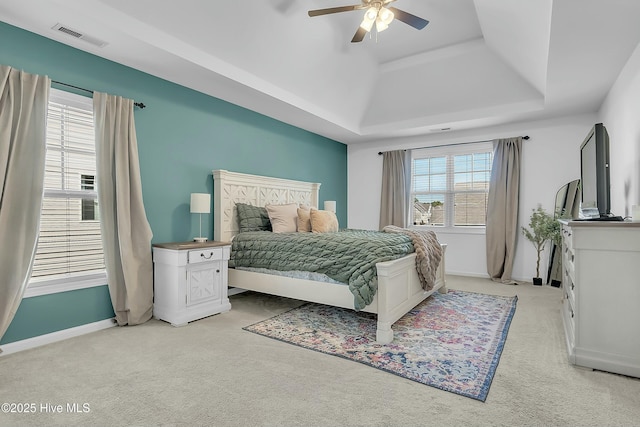 bedroom featuring ceiling fan, a tray ceiling, and light carpet