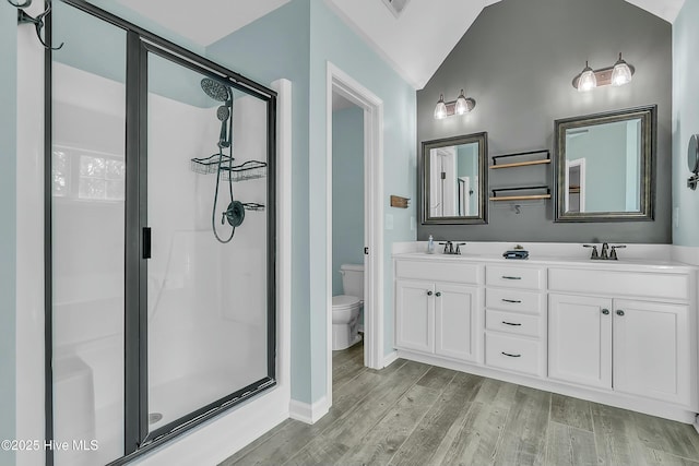 bathroom featuring hardwood / wood-style floors, a shower with shower door, toilet, and vaulted ceiling