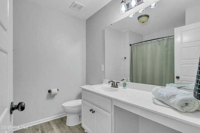 bathroom featuring vanity, wood-type flooring, walk in shower, and toilet