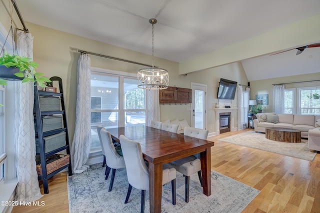 dining space with lofted ceiling, a chandelier, and light hardwood / wood-style flooring