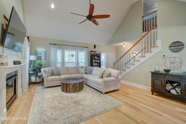 living room with a tile fireplace, wood-type flooring, ceiling fan, and high vaulted ceiling