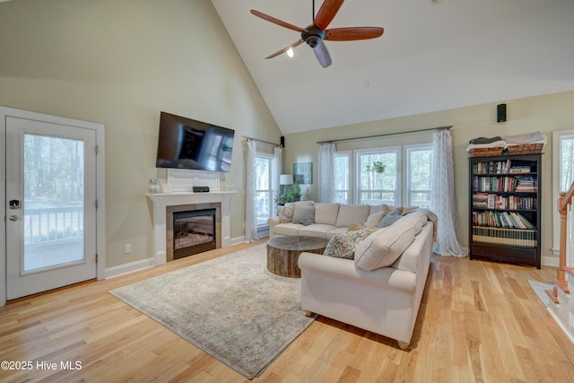 living room with ceiling fan, high vaulted ceiling, a fireplace, and light hardwood / wood-style floors