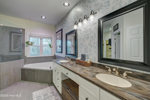 bathroom featuring a relaxing tiled tub and vanity