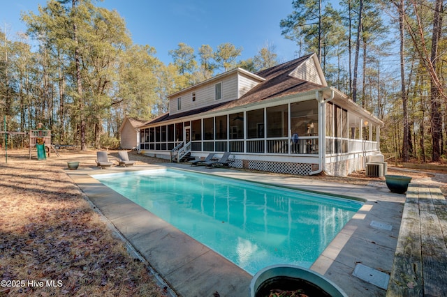 rear view of house featuring central AC, a playground, and a sunroom